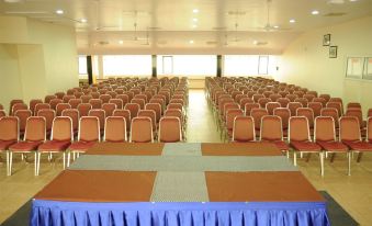 an empty conference room with rows of chairs and a stage , ready for an event at National Park Residency