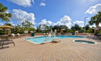 a large swimming pool with a diving board and lounge chairs in a brick - paved area at Hilton Garden Inn Tampa/Riverview/Brandon