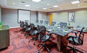 a conference room with a long table surrounded by black chairs and green glasses on the tables at Hilton Garden Inn Chesterton