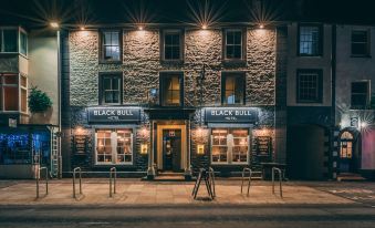 a nighttime scene of a building with two windows , one on the left side and the other on the right side at Black Bull Hotel