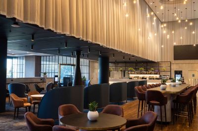 a modern , stylish restaurant with wooden tables and chairs , surrounded by green plants and lights at Oval Hotel at Adelaide Oval, an EVT hotel