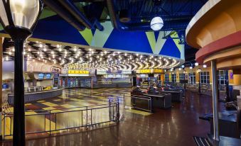 a large , well - lit movie theater with multiple projectors and screens , as well as tables and chairs for customers to sit and watch movies at Disney's All-Star Movies Resort