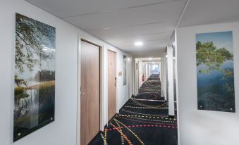 a hallway with a carpeted floor and several paintings on the walls , leading to several doors at K Hotel