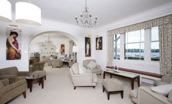 a spacious living room with white walls , hardwood floors , and various furniture including couches , chairs , and tables at Low Wood Bay