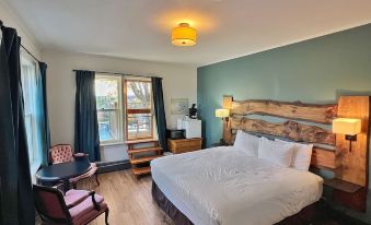 a large bed with a wooden headboard is in the center of a room with a window , chair , and lamp at Inn at the Falls