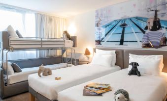 a hotel room with two beds , one on top of the other , and a teddy bear placed on one of the beds at Novotel Dijon Sud