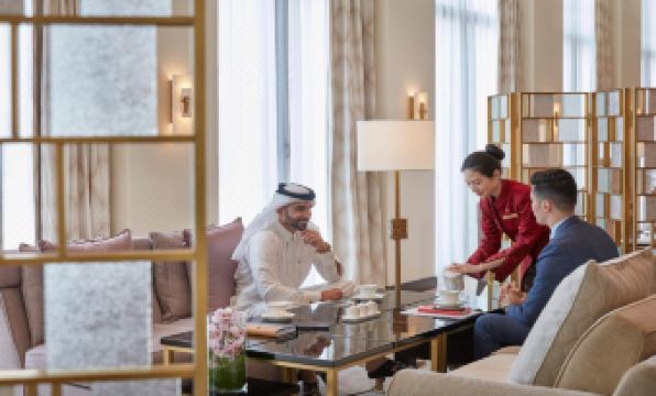 a man and a woman are sitting at a table in a hotel room , enjoying a cup of tea at Mandarin Oriental, Doha