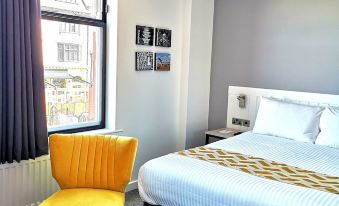 a cozy bedroom with a large bed and a yellow chair placed near the window at Mode Hotel Lytham