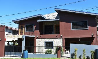 a two - story house with a brown facade and a black fence in front of it at Lucina's