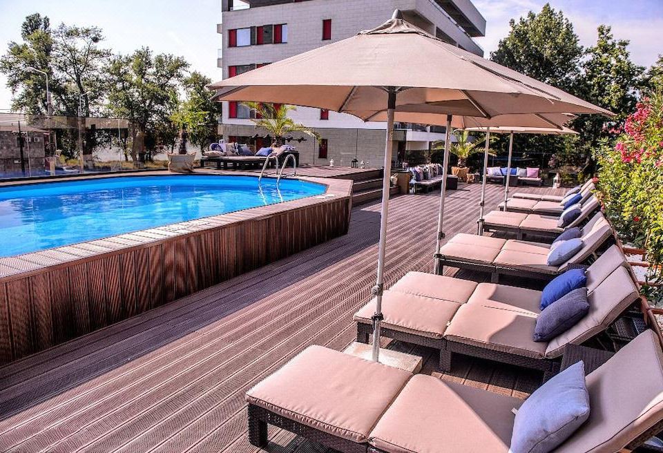 a poolside area with several lounge chairs and umbrellas , providing a comfortable seating for guests at Richmond Hotel