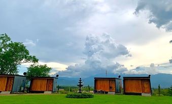 a grassy field with three wooden houses , one of which is a house on a hill at The Sunnery Ville