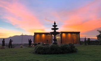 a sunset view of a building with a fountain in front and people standing around at The Sunnery Ville