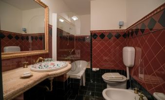 a bathroom with a sink , toilet , and bathtub , along with red and black tile walls at Hotel Capital