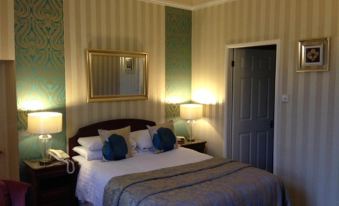 a large bed with blue and white bedding is in a room with striped walls at Hardwicke Hall Manor Hotel