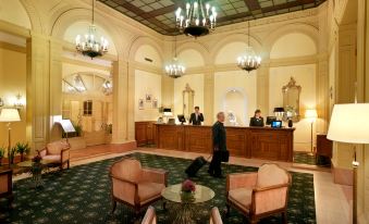 a reception area with a man in a suit and woman standing at the front desk at Sina Brufani