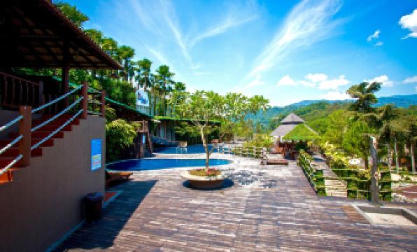 a tropical resort with a swimming pool , umbrellas , and palm trees under a clear blue sky at The Waterway Villa