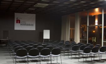 an empty conference room with rows of black chairs arranged in front of a white board at Hotel Navarras