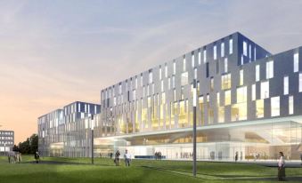 a modern building with a grassy field in front and people walking on the grass at Courtyard Munich Garching