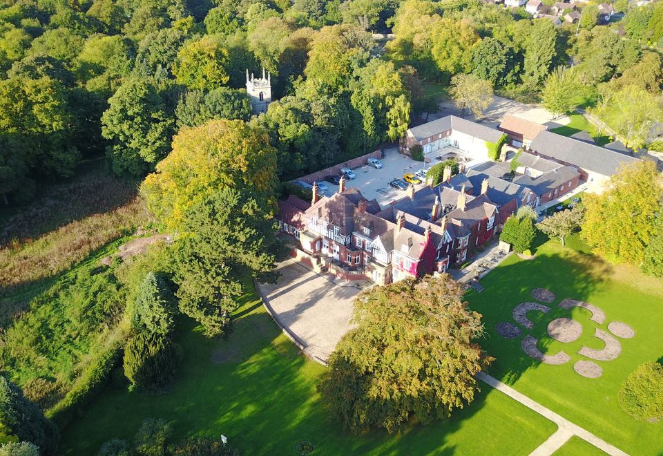 an aerial view of a large building surrounded by trees and a park in the background at Healing Manor Hotel