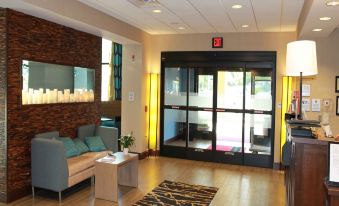 a modern and stylish lobby area with wooden flooring , white walls , and large windows , featuring a reception desk , seating area , and a glass at Hampton Inn & Suites by Hilton Stroudsburg Pocono Mountains
