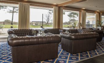 a room with two brown leather couches and large windows overlooking a golf course , creating a relaxing atmosphere at Hotel Marina