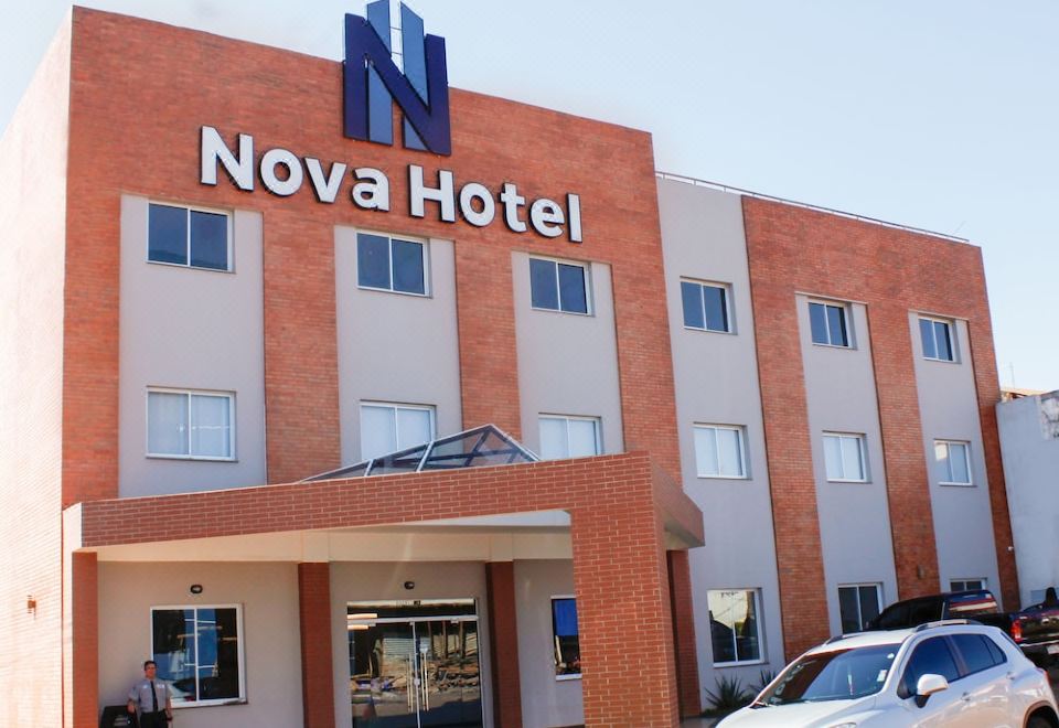 "a red brick hotel building with the words "" nova hotel "" written on it , surrounded by greenery" at Nova Hotel
