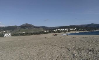 a grassy field with a body of water in the distance , surrounded by hills and mountains at Anastasia