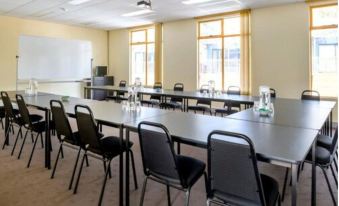 a large conference room with multiple rows of chairs arranged in a semicircle around a long table at Discovery Parks - Hobart