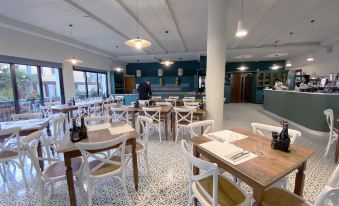 a large , modern restaurant with wooden tables and white chairs , surrounded by a blue and white tiled floor at Hotel Astoria