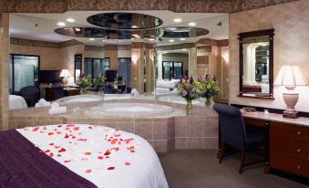 a luxurious hotel room with a bed , rose petals , and a hot tub , as well as a dining area and a bathroom at Paradise Stream Resort