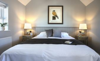 a large bed with white linens and a black throw blanket is in a room with two lamps at The Ferry Boat Inn