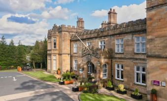 "a large , stone building with a sign that reads "" the palace "" is surrounded by greenery and potted plants" at Mercure Blackburn Dunkenhalgh Hotel & Spa