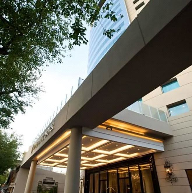 a modern building with a large archway entrance , surrounded by trees and a clear sky at DiplomaticHotel
