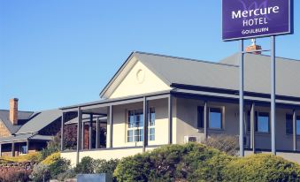 a hotel with a large sign on the front , located in a grassy area near trees at Mercure Goulburn