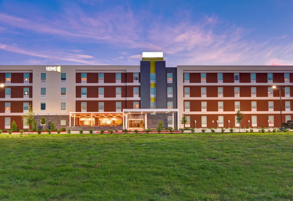a large hotel with a red and brown color scheme , surrounded by green grass and trees at Home2 Suites by Hilton la Porte
