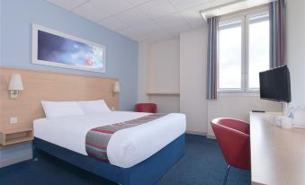 a hotel room with a blue bed , white sheets , and a television mounted on the wall at Travelodge Oswestry