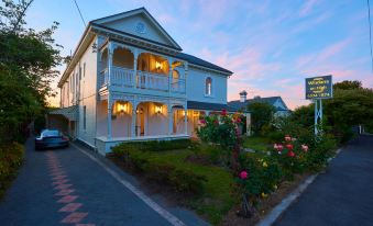 a large white house with a balcony and balcony railings is surrounded by greenery and flowers at Windarra on High