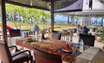 The dining room of the restaurant has a table with chairs and offers a scenic view of the water at Hotel Sudara Beach Resort