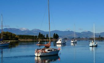 a serene body of water with several sailboats floating on it , surrounded by mountains in the background at Greenwood Park
