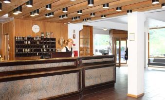 a woman standing behind a counter in a room with wooden walls and ceiling lights at Stalheim Hotel