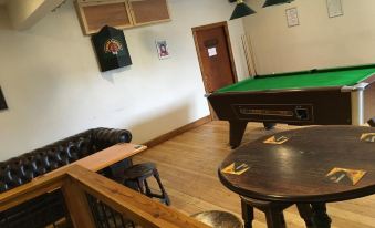 a pool table is in the middle of a room with several chairs and tables at The White Horse