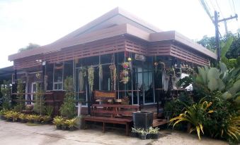 a wooden house with a large glass window and several tables and chairs outside , surrounded by plants at M Grand Hotel