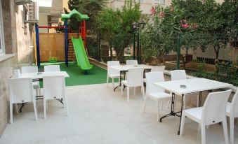 an outdoor dining area with white tables and chairs , as well as a playground with a slide at Palm Beach Hotel