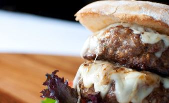 a close - up image of a delicious burger with meat and cheese on a wooden board at The Anchor Inn