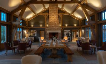 a large dining room with wooden beams on the ceiling , a fireplace , and a table surrounded by chairs at Retreat East