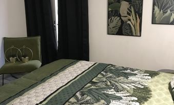 a bedroom with a bed featuring a green and white patterned blanket , two paintings on the wall , and a chair at Marina