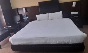 a large bed with white sheets and a black headboard is in a hotel room at Hotel Samana