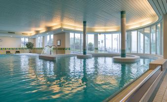 an indoor swimming pool surrounded by windows , allowing natural light to fill the space at Arenas Resort Victoria-Lauberhorn