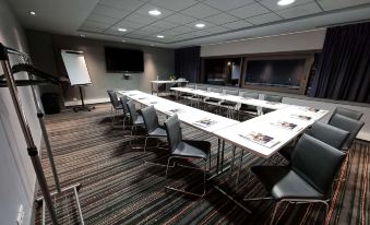 a conference room with a long table , chairs , and a television mounted on the wall at Ibis Styles Caen Centre Gare