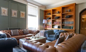 a well - decorated living room with two brown leather couches , a wooden coffee table , and several potted plants at The Celtic Royal Hotel